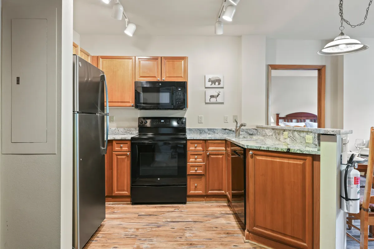 This close-up kitchen scene features black appliances, granite countertops, and wooden cabinetry, with artistic touches on the walls. The setting conveys an atmosphere ideal for both everyday cooking and festive gatherings, capturing the heart of the chef’s kitchen experience.