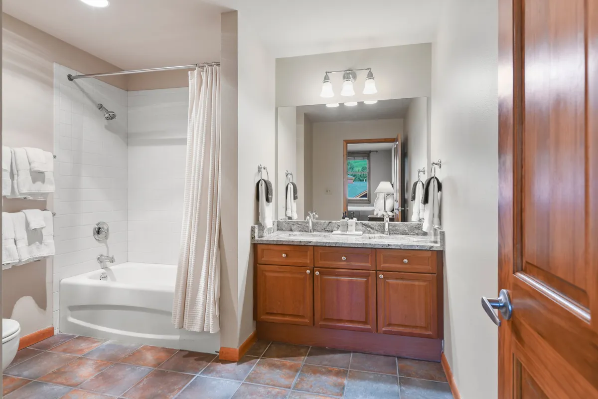 A spa-inspired bathroom with a double sink vanity, a bathtub ideal for soaking, a large mirror, and a spacious shower area. The setting is serene and inviting, with clean design and soothing tones.