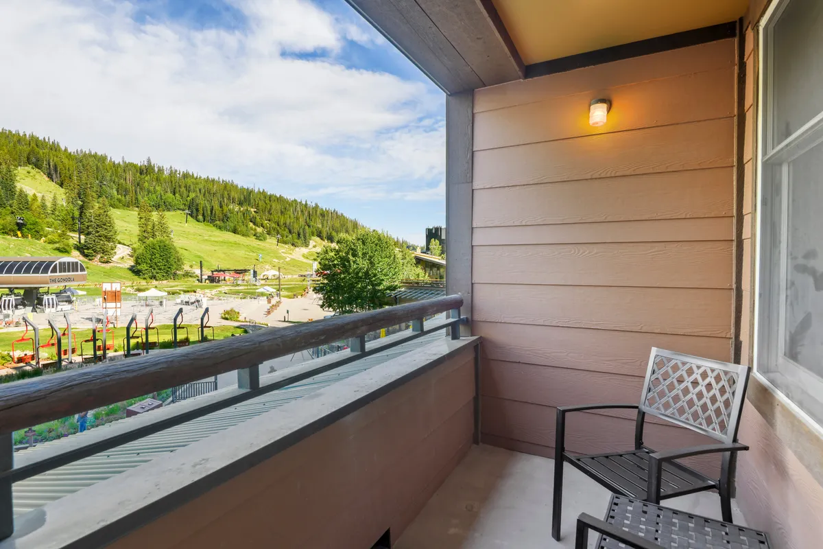 This image features a peaceful private deck with a balcony railing and comfortable outdoor furniture, set against a stunning mountain backdrop. The early morning light highlights the serene setting, perfect for enjoying a morning coffee or relaxing while soaking in the expansive views.